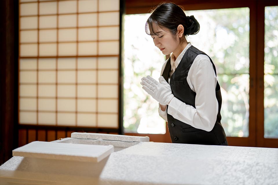 葬儀スタッフが棺に向かって手を合わせている様子
